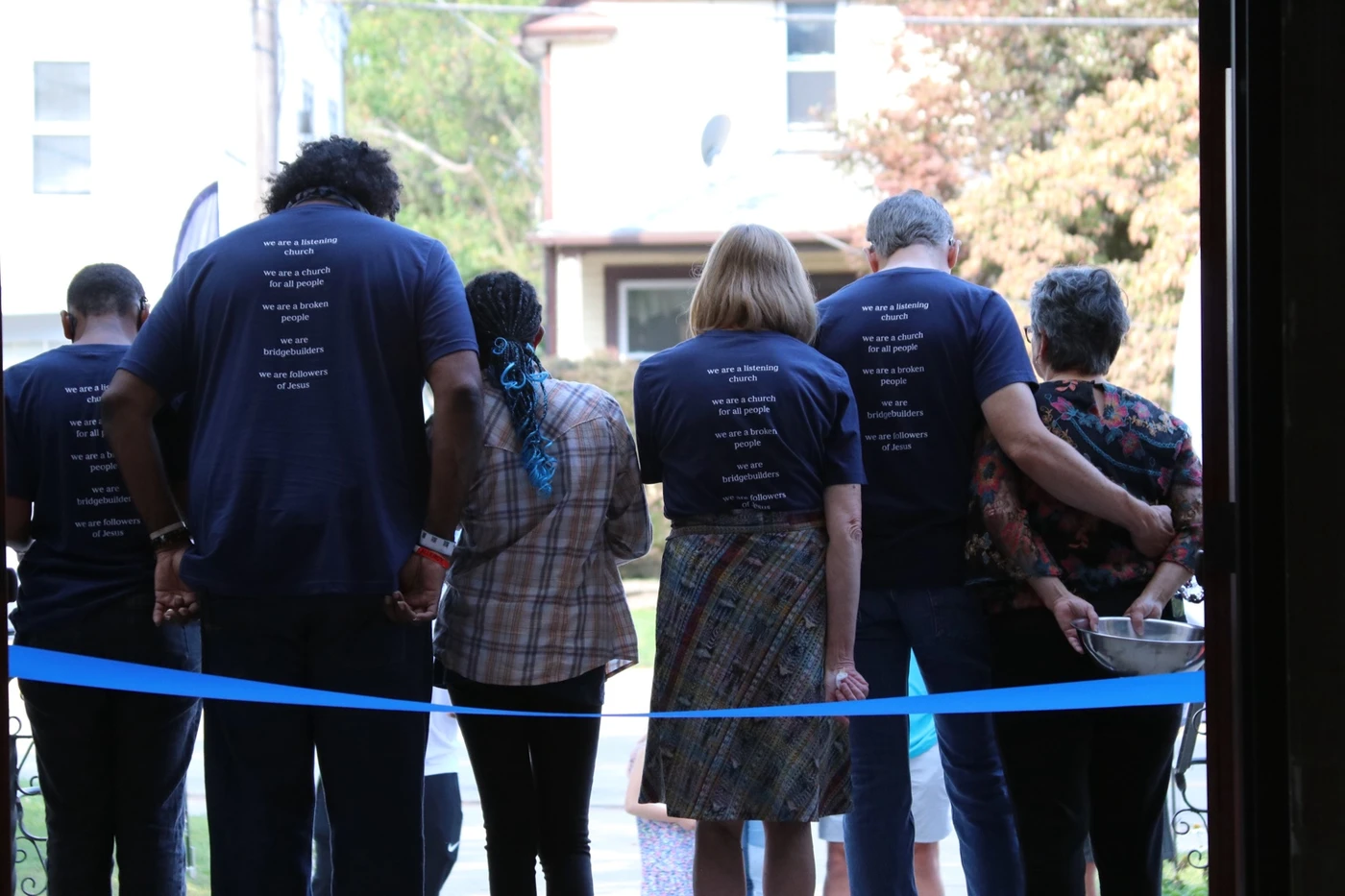 Church family members standing arm in arm at the anniversary ribbon