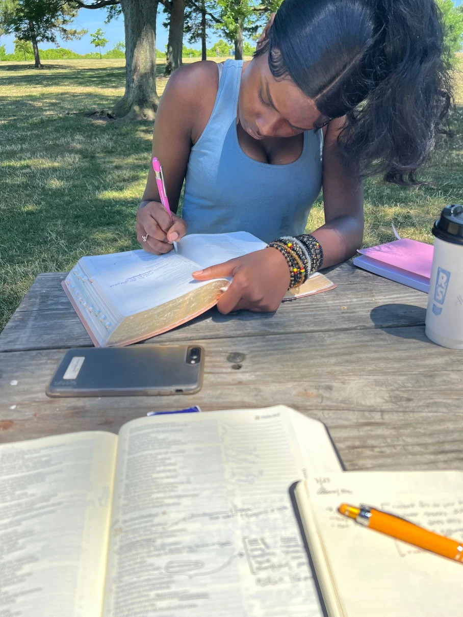 A student reading and writing with an open Bible